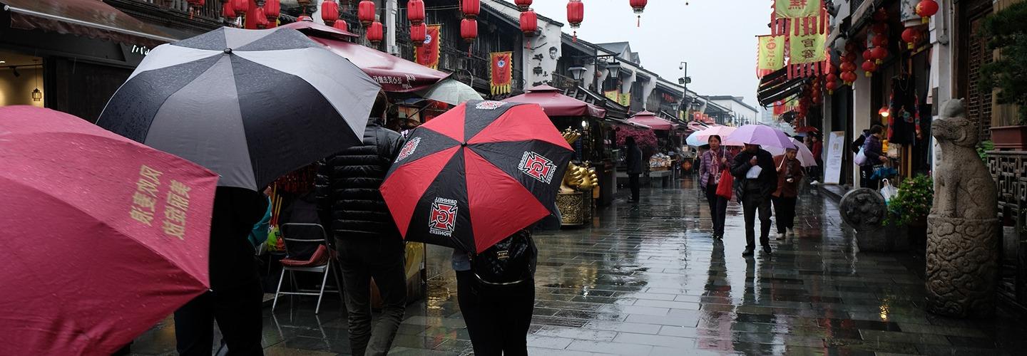 在挂满中国灯笼的街道上，学生举着bet36体育投注足彩网伞